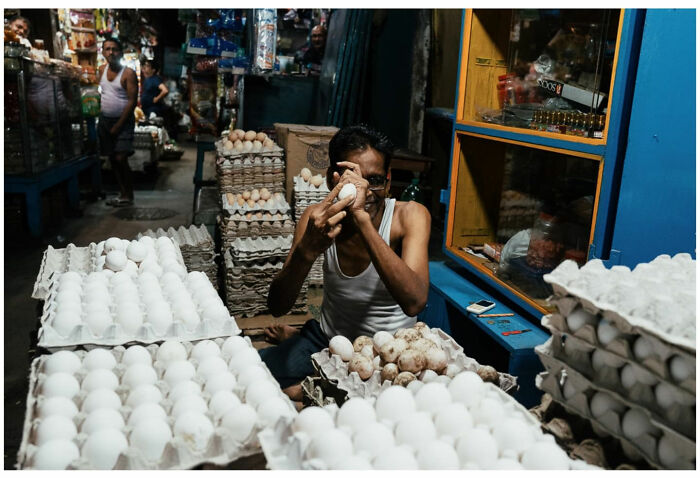 Man in a busy Asian street market handling eggs, capturing raw and captivating moments from the streets of Asia and beyond.
