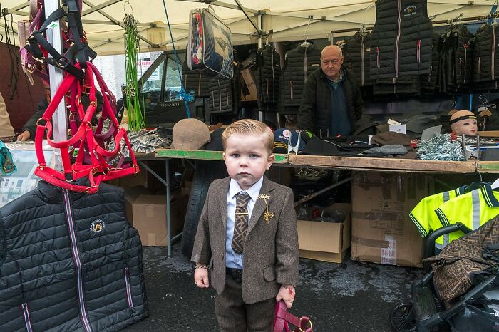 Young boy in a brown suit at a market stall, capturing raw and beautiful life on the margins of modern Ireland.