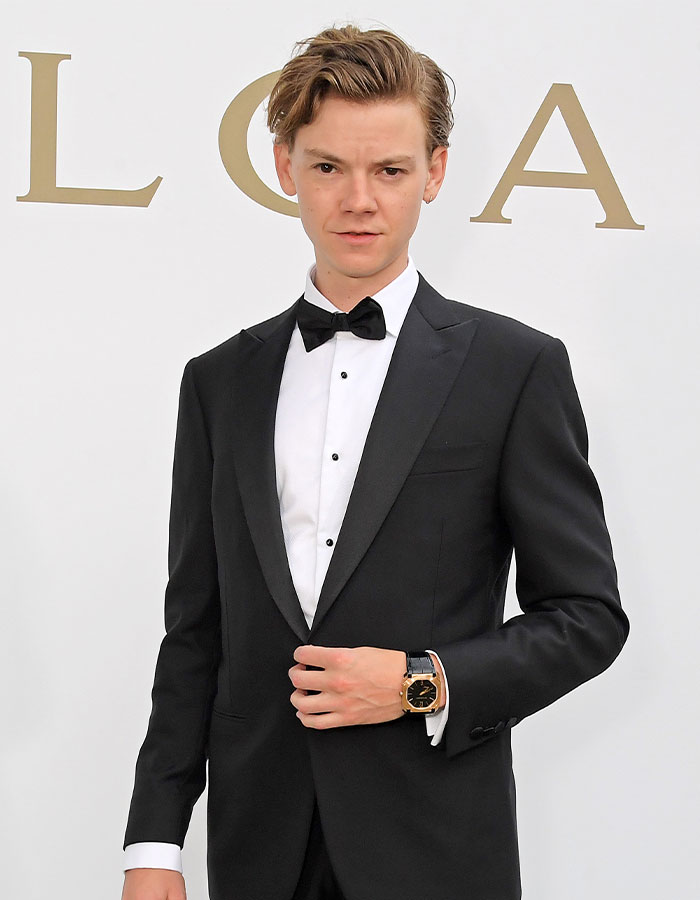 Young celebrity wearing a black tuxedo and bow tie, looking stylish and youthful at a formal event.