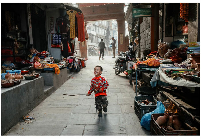A joyful child running through a vibrant street market capturing raw and captivating moments from the streets of Asia and beyond.