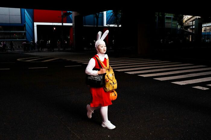 Person dressed in a bunny costume walking on a dark street, capturing a unique moment in street photography.