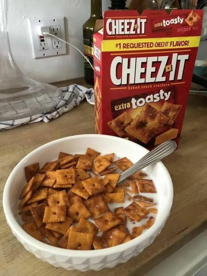 Bowl of Cheez-It crackers with milk, next to an open Cheez-It box, showcasing a cursed food picture.
