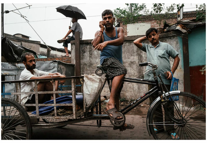 Men in a street scene in Asia with a man on a bicycle cart, showcasing raw and captivating moments through the lens of a vagabond.