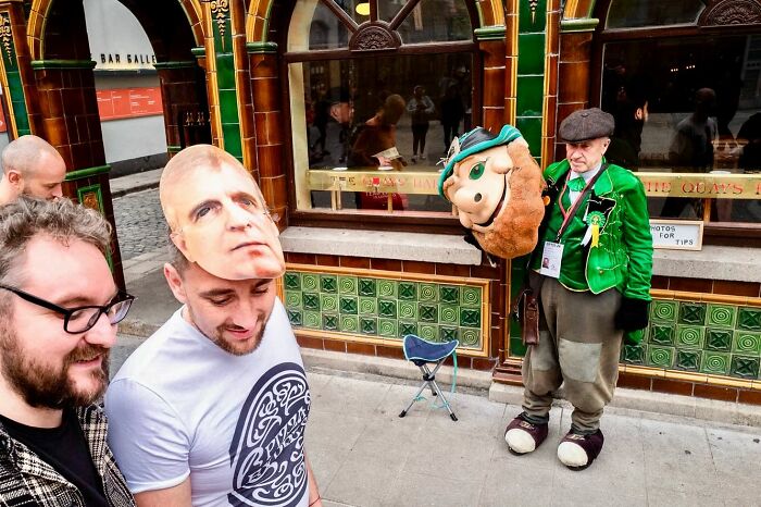 Street photographer captures candid moment with unusual masks and vibrant street scene outside a tiled building.