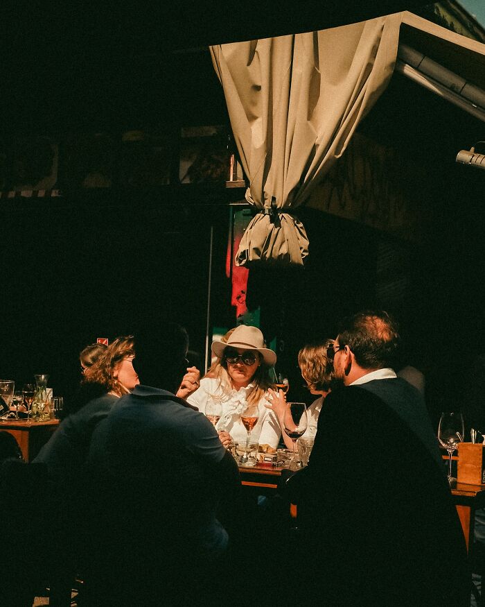 Group of people enjoying drinks at an outdoor urban café, captured in a Helsinki-based photographer's street photo.
