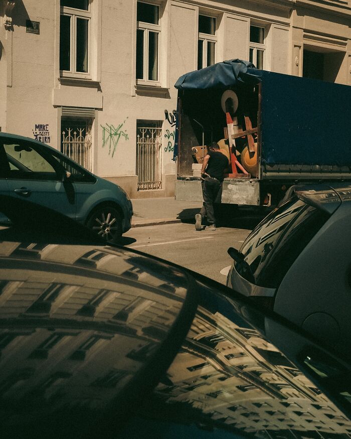 Urban photo of a man unloading a truck in a city street scene, capturing real moments by Helsinki-based photographer.
