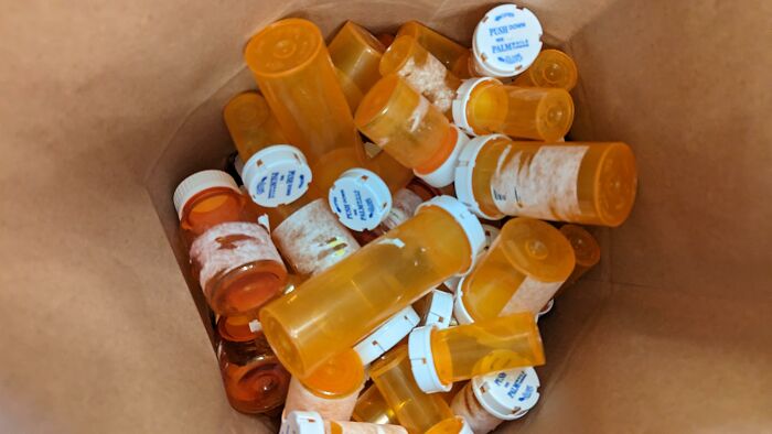 Paper bag filled with multiple old prescription pill bottles showing disturbing things found after a loved one’s death