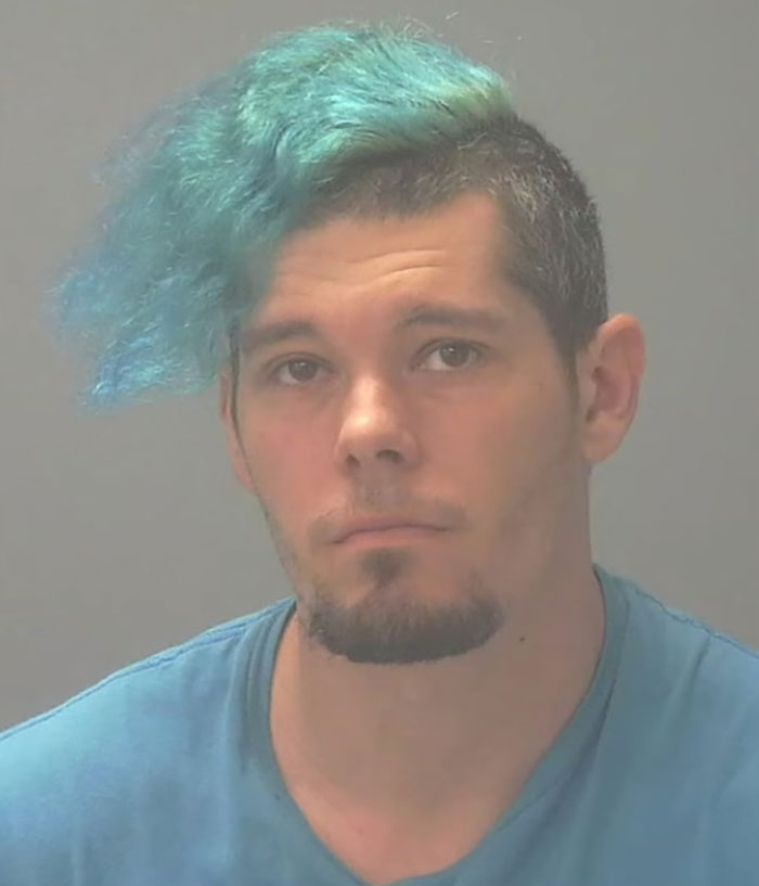 Mugshot of a man with blue hair wearing a blue shirt connected to a captive woman's brave cry for help and rescue.