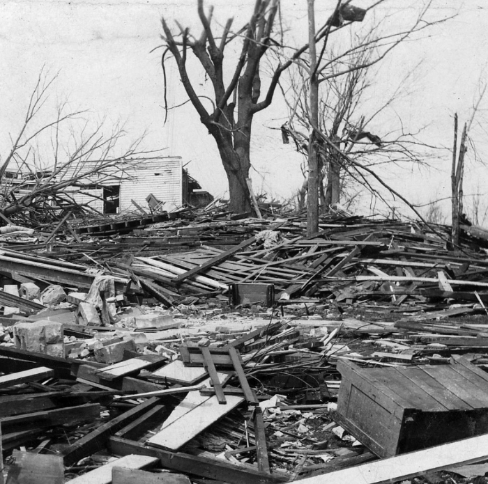 Black and white image of extensive tornado damage with debris and broken trees, depicting the worst tornado in US history.
