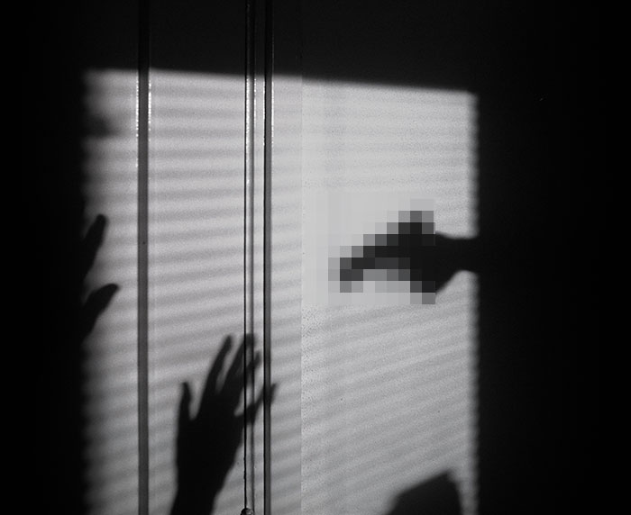 Shadow of a woman&rsquo;s hands raised defensively with a gun pointed at her, illustrating marriage isn't easy and viral shooting story.