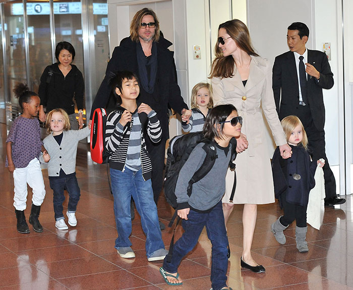 Brad Pitt walking with children in an airport, highlighting Brad Pitt cut off all contact with sons news.