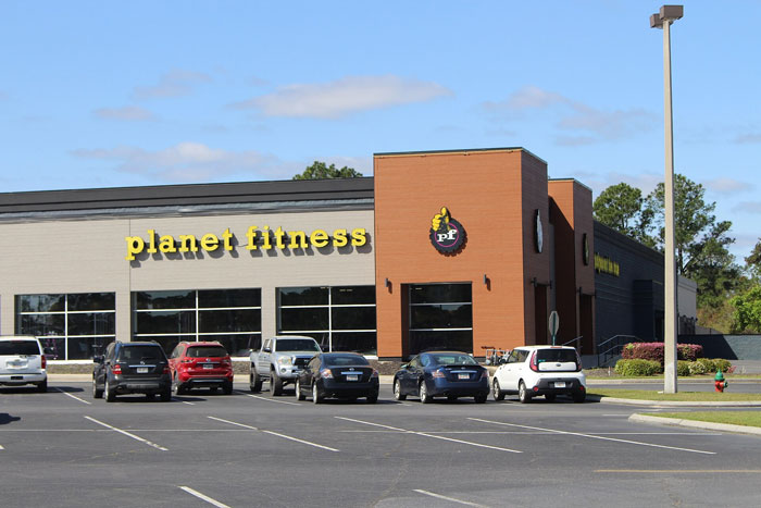 Planet Fitness gym exterior with cars parked in front under a clear sky, relating to wild things people say they've seen.