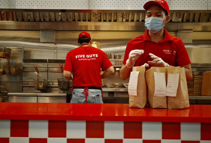 Two fast food workers in red uniforms packing orders at a counter, highlighting people describing biggest life mistakes.