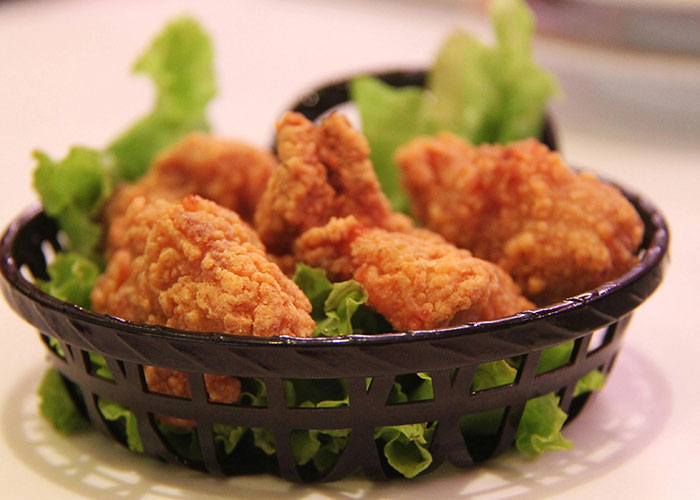 Basket of crispy fried chicken wings on a bed of lettuce representing buffet workers' wildest encounters.