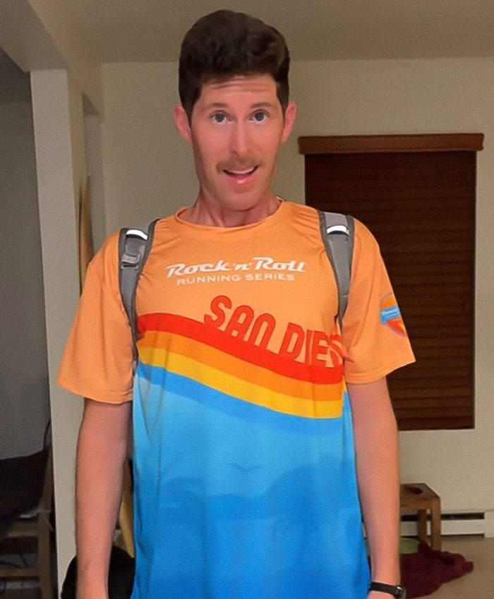 Man wearing a San Diego marathon shirt with a backpack, prepared to run a marathon with zero training.