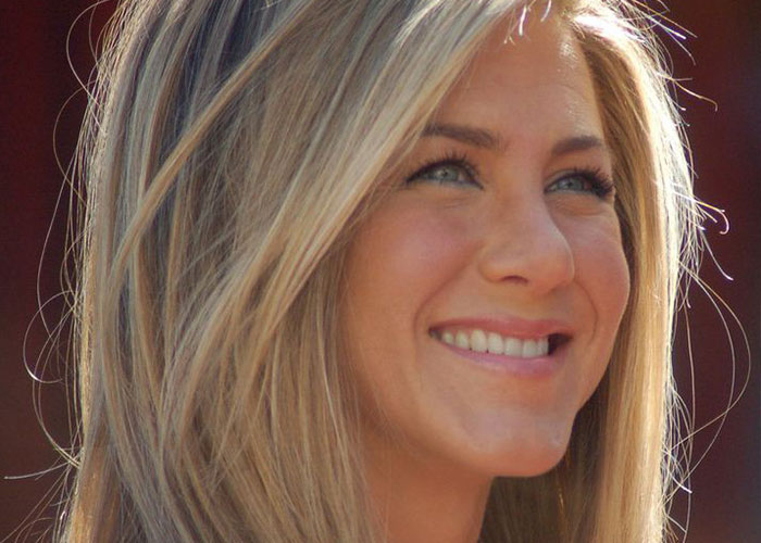 Close-up of a smiling female celebrity with blonde hair, representing celebrities before fame in a candid moment.