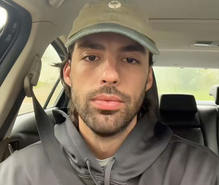 Man wearing a cap and hoodie sitting inside a car with seatbelt fastened illustrating safe driving facts.
