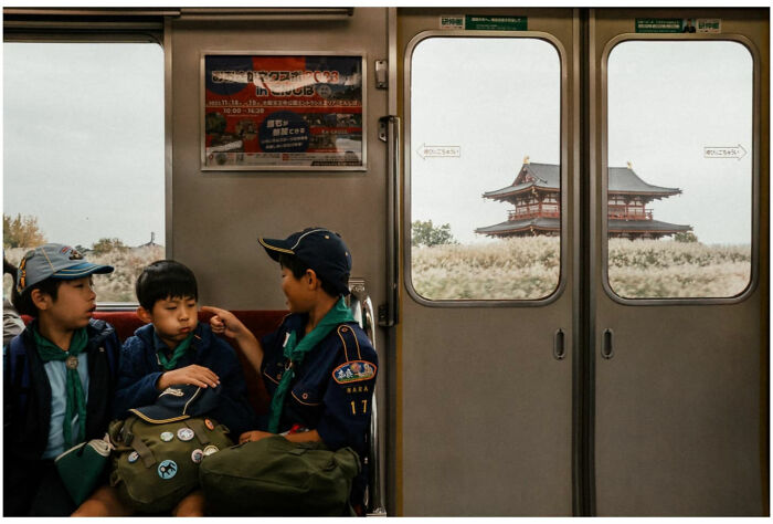 Three boys in scouting uniforms share a moment inside a train, capturing raw and captivating street moments in Asia.