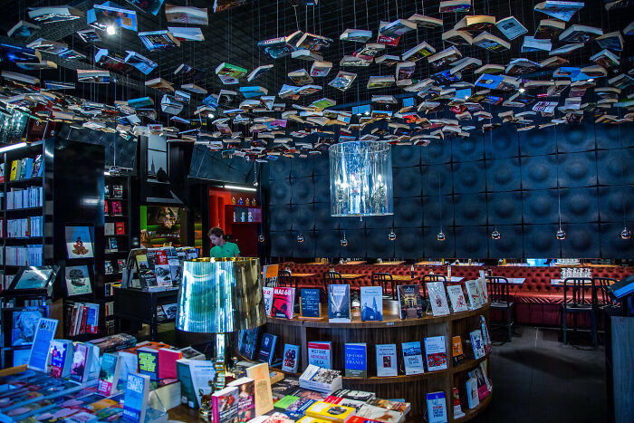 Interior of a stunning bookstore with books hanging from the ceiling and shelves filled with colorful books in an impressive setting.