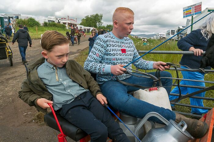 Two boys sitting on a cart holding reins, capturing life on the margins of modern Ireland in a candid street scene.