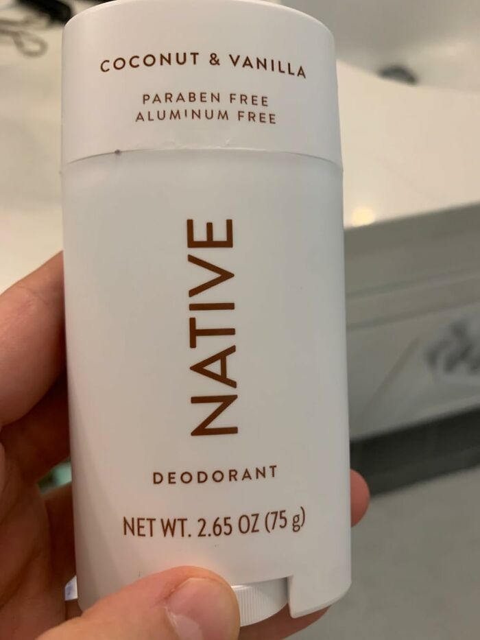 Hand holding a chemical-free Native deodorant labeled coconut and vanilla, paraben and aluminum free product.