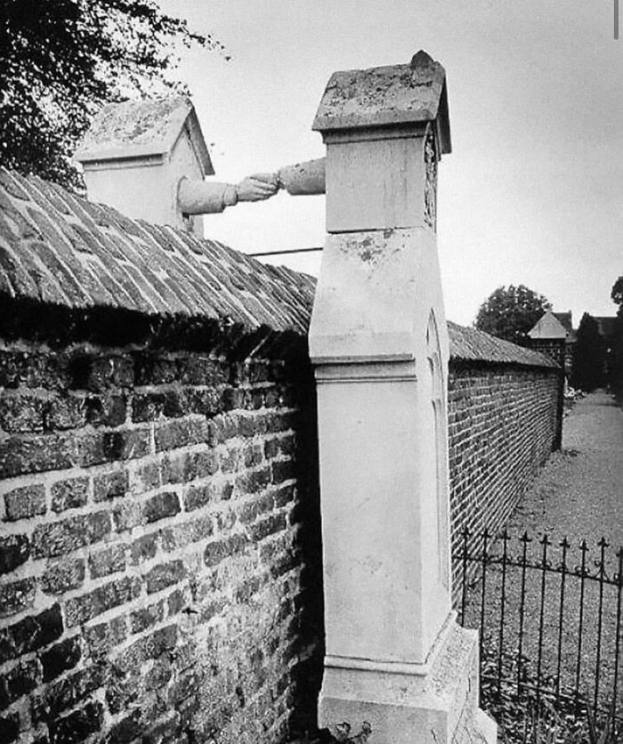 Stone monuments with carved arms shaking hands over a brick wall, showcasing a unique archaeology world historical moment.