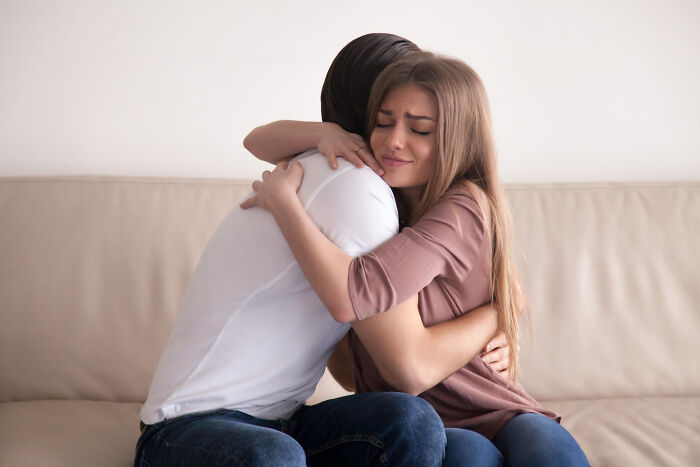 Young woman hugging a man on a couch, illustrating small signs that reveal a troubled childhood.