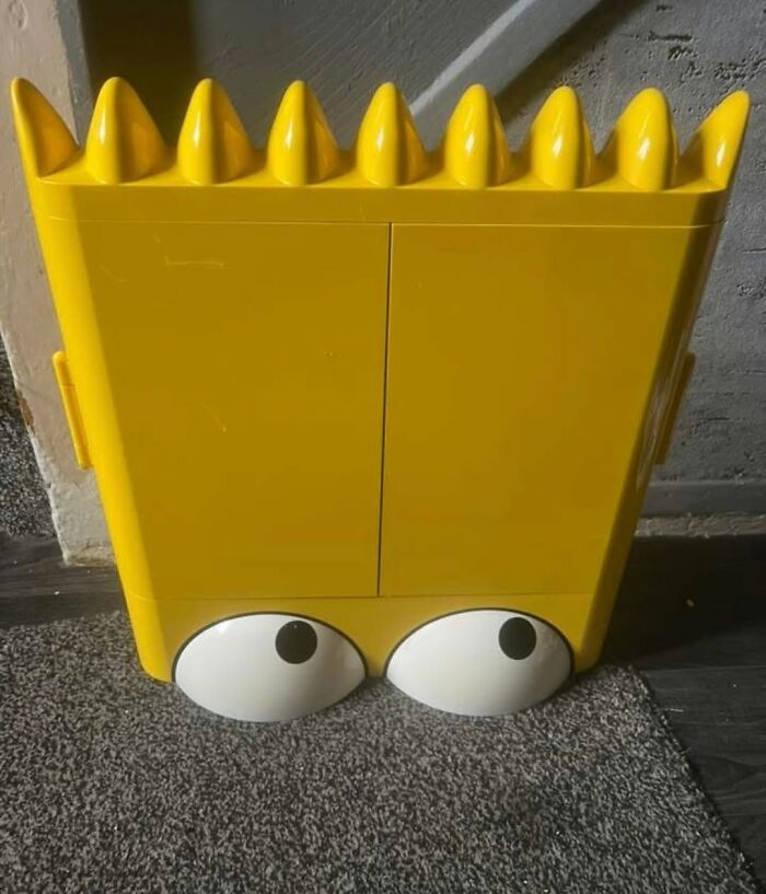 Yellow storage cabinet with cartoon-style eyes and spiked top, a cool secondhand find displayed indoors.