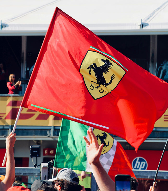 Ferrari flags waving at a crowded F1 event, symbolizing support for Michael Schumacher's legendary racing career.
