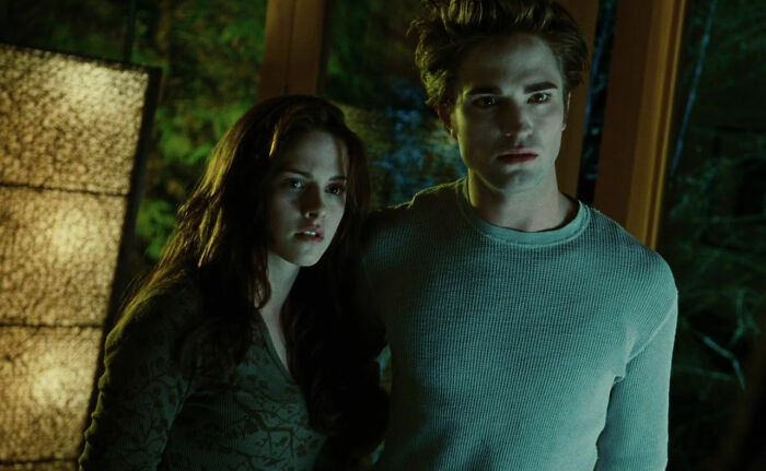 A tense scene from a romantic but toxic movie showing a young couple in dim lighting indoors.