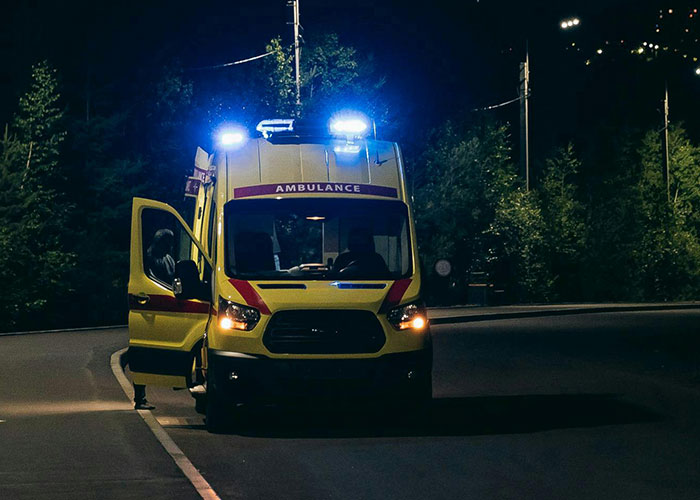 Ambulance with flashing lights parked at night, capturing a dramatic take one for the team moment in action.
