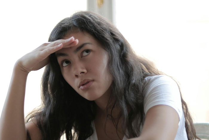 Young woman looking concerned and stressed indoors, illustrating toxic dating trends people weirdly accept as normal.