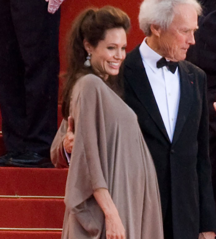 Actress smiling in a taupe dress on red carpet with a man in a black tuxedo, unrelated to Brad Pitt contact news.