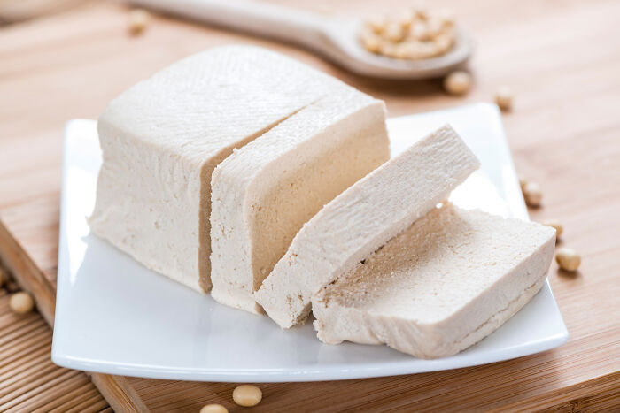 Sliced tofu on a white plate with soybeans in the background, highlighting best processed foods for weight loss.