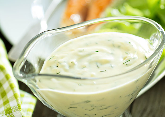 Close-up of creamy dressing in a glass bowl, highlighting a common buffet item related to buffet workers' wildest encounters.