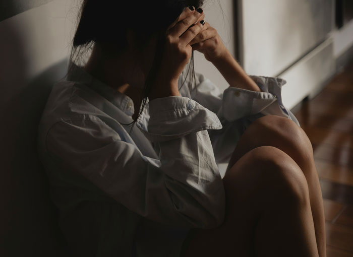 Person sitting on floor in shadow with hands on head, reflecting on intense therapy revelations and emotional breakthrough moments.