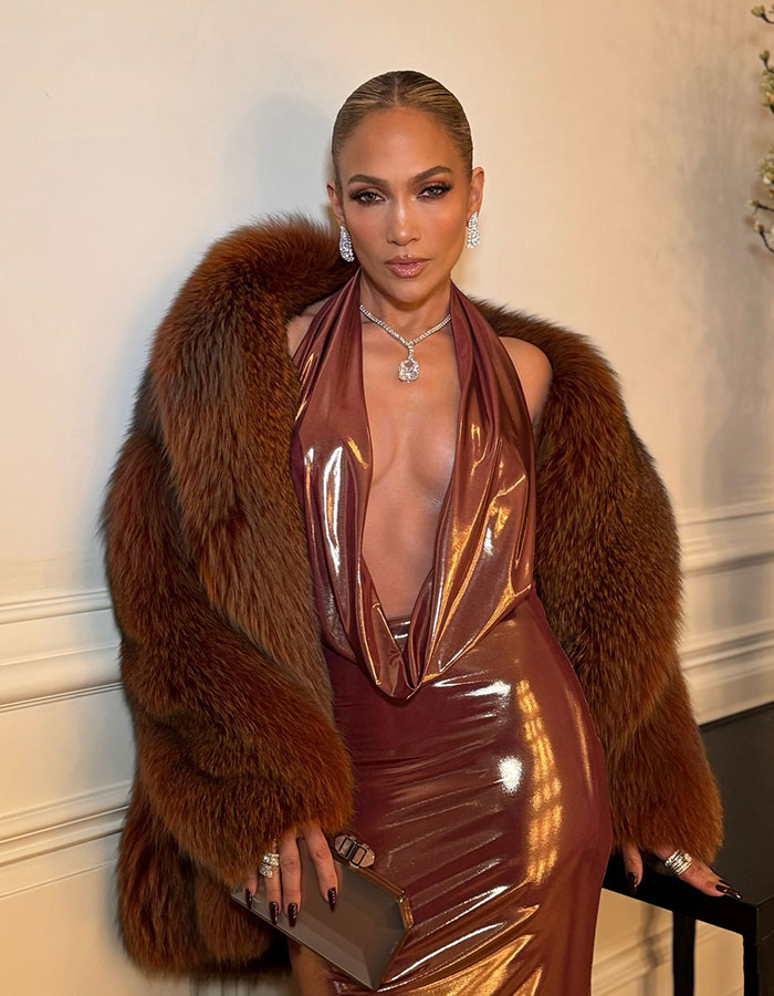 Celebrity wearing a shiny bronze dress and luxurious fur coat, showcasing looks way younger than actual age.