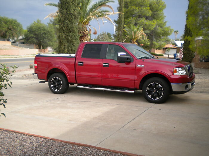 Red pickup truck parked on driveway with trees and houses in the background illustrating police dragged into utter nonsense.