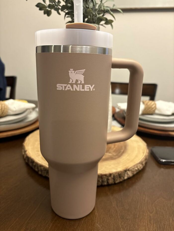 Stanley insulated travel mug with handle and straw, perfect for staying refreshed on a beach day with sun, sand, and snacks.