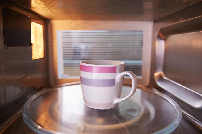 Mug inside a microwave with light on, illustrating a common American kitchen scene related to cultural habits.