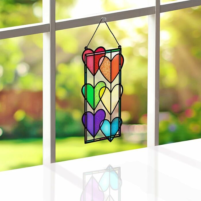 Colorful stained glass hearts in a window hanging, representing pride pieces for all year celebration and decoration.