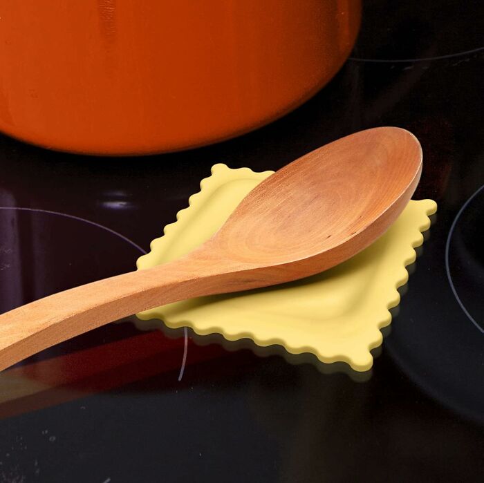 Wooden kitchen spoon resting on a yellow trivet on a stovetop, a useful item from your kitchen Prime Day wishlist.