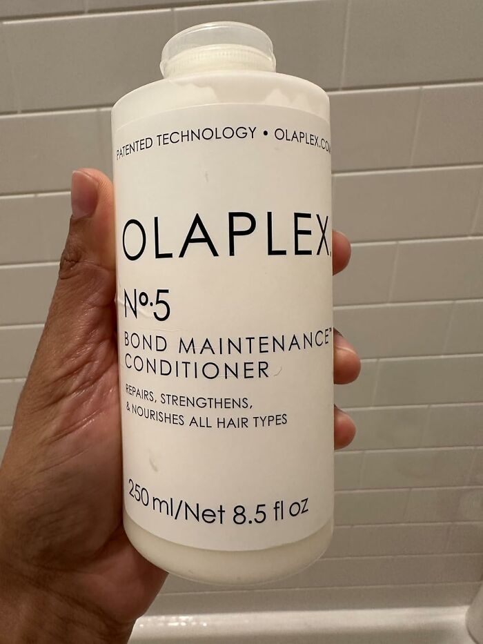 Hand holding a bottle of Olaplex No 5 Bond Maintenance Conditioner, featured in Prime Day deals.