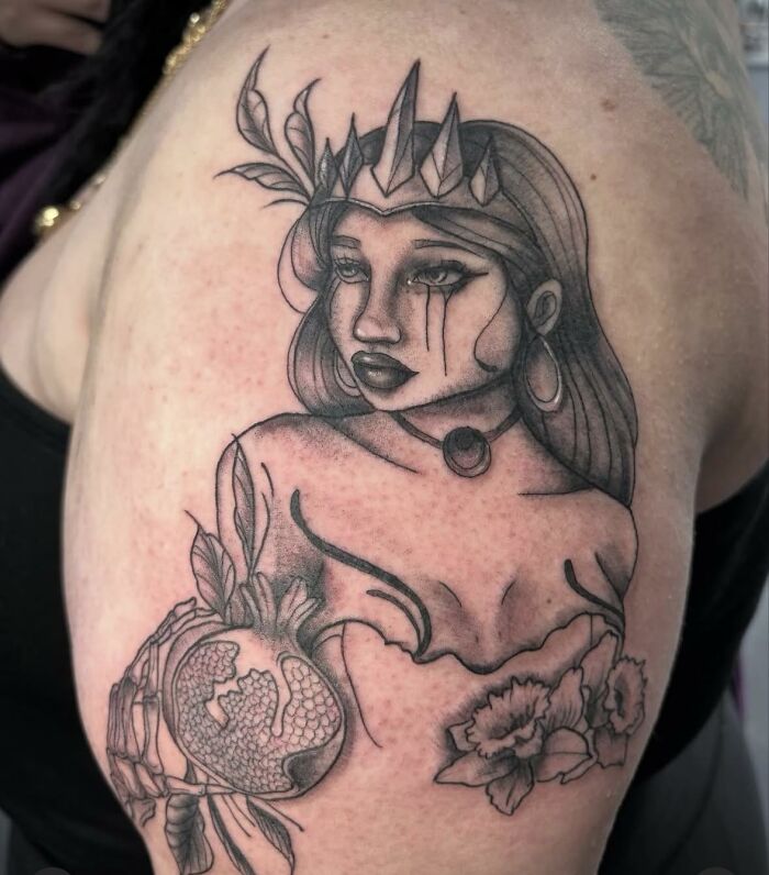 Black and grey tattoo of a woman with a crown, holding a pomegranate, showcasing hilariously bad tattoos and inkshaming moments.