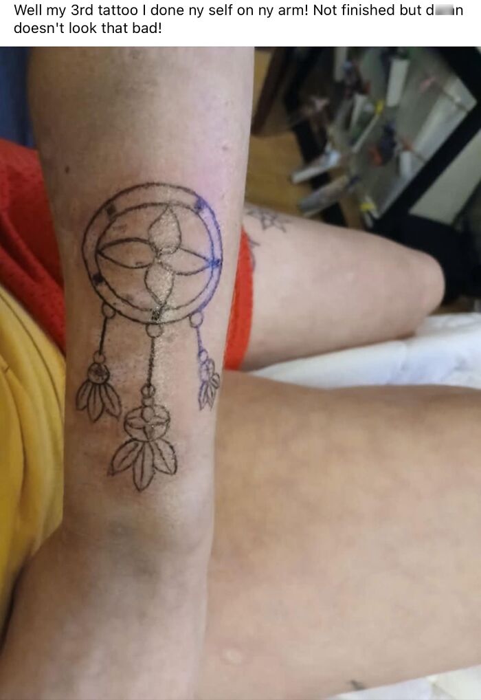 Hand-drawn dreamcatcher tattoo on forearm, showcasing a hilariously bad tattoo in a casual home setting.