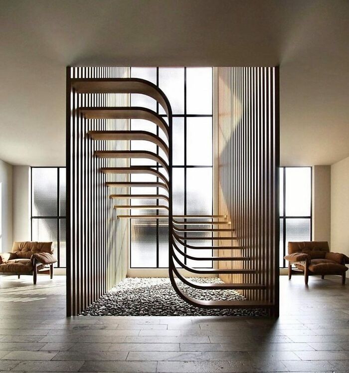 Modern death stairs design with curved wooden steps and vertical slats in a minimalist, light-filled living space.