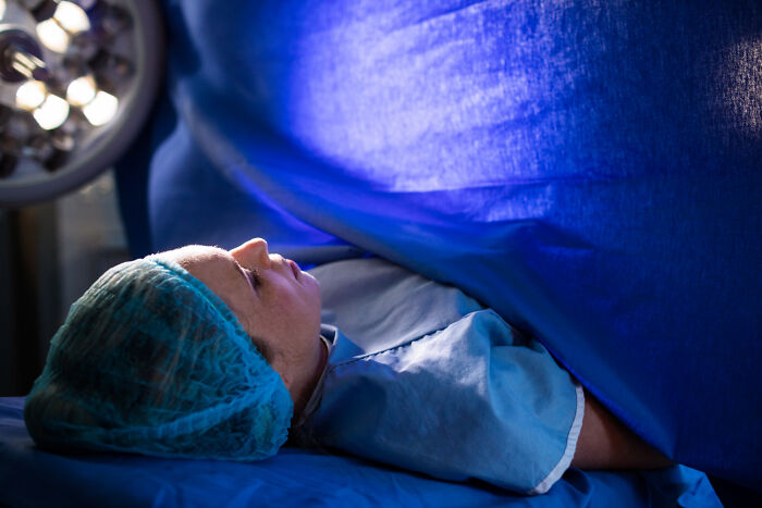 Patient lying on hospital bed under blue surgical drapes during a medical procedure, illustrating hidden family secrets.