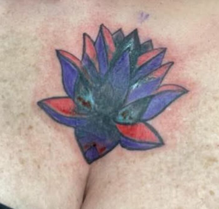 Hilariously bad tattoo of a multicolored flower with uneven shading and unclear design on light skin.