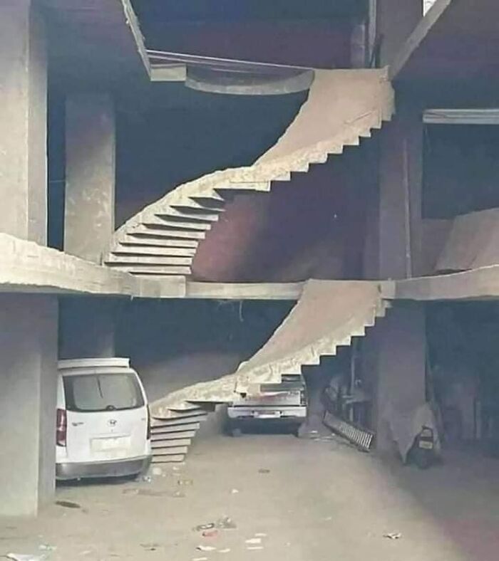 Concrete death stairs with a dangerous and impractical design in an unfinished building parking area.