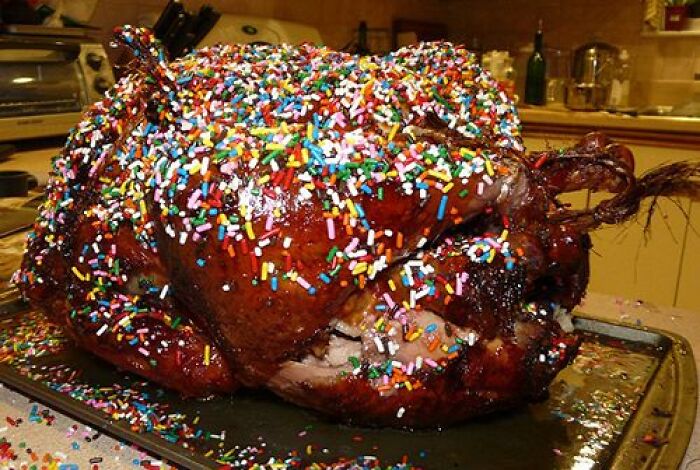 Roast turkey covered in colorful candy sprinkles on a kitchen tray as a cursed food picture.